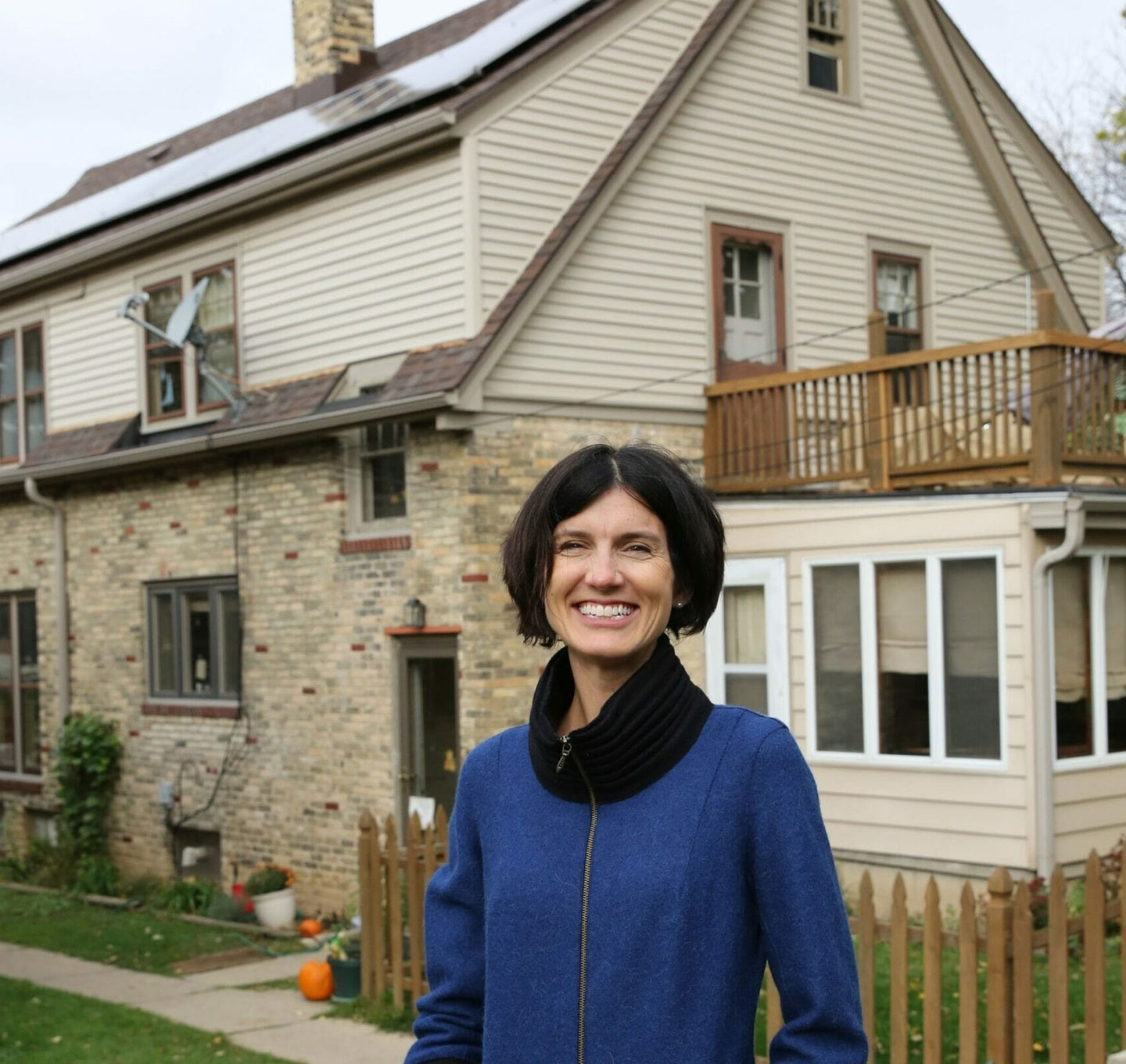 A happy customer standing in front of their home with solar on the roof.